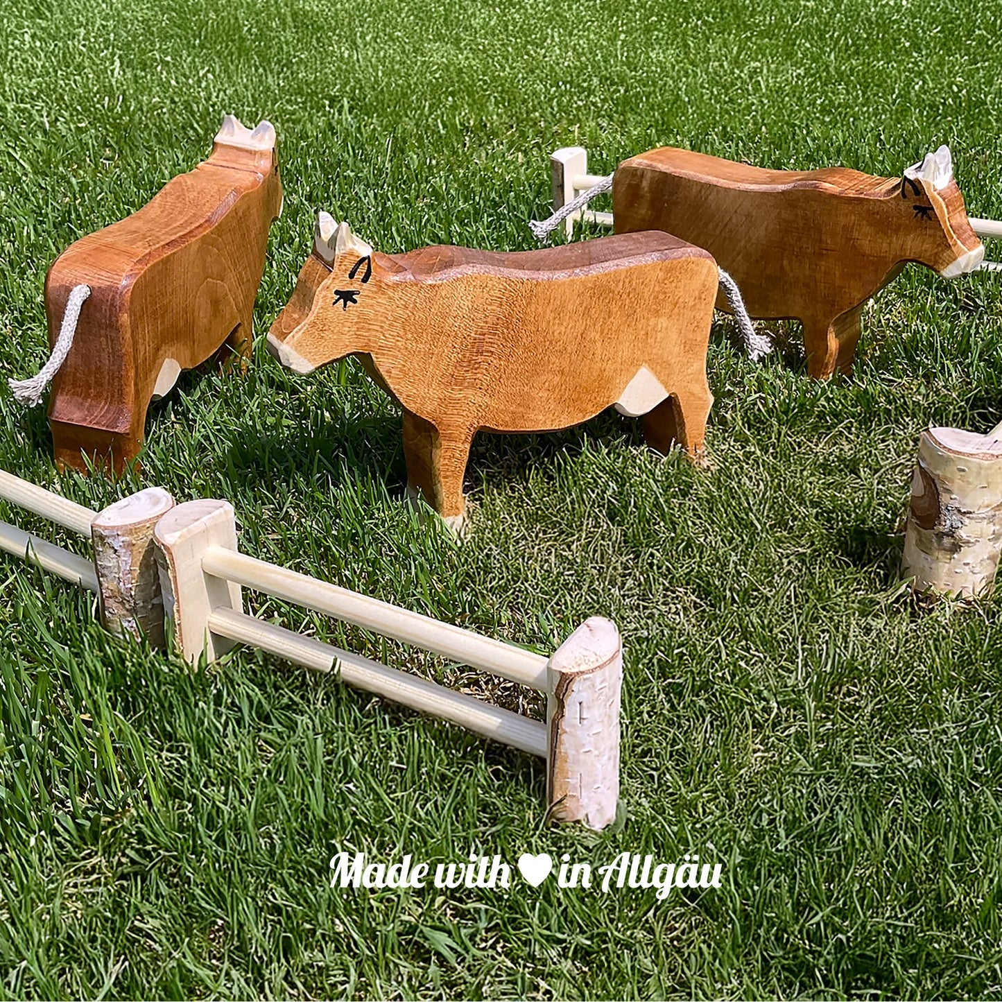 Handgefertigtes Holzspielzeug Kuh Braunvieh von Allgäuer Holztiere, braun und grau bemalt mit pflanzlichen Farben, stehend in natürlicher Weide- oder Waldumgebung, aus bayerischem Ahornholz gefertigt, nachhaltig produziert im Allgäu und für Kinder ab 3 Jahren geeignet.