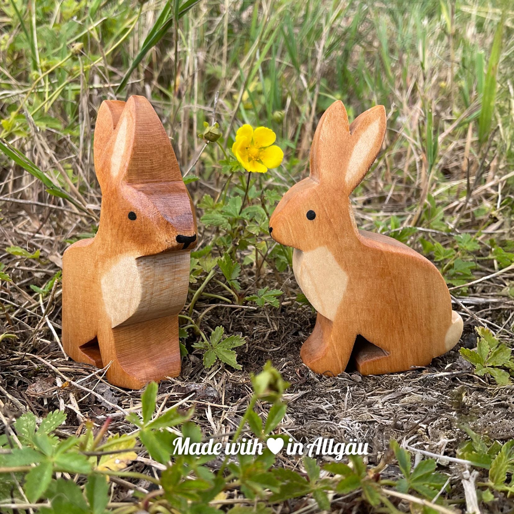 Handgefertigtes Holzspielzeug Feldhase Häsin von Allgäuer Holztiere, braun bemalt mit pflanzlichen Farben, sitzend in natürlicher Umgebung auf Moos oder Feldboden, aus bayerischem Ahornholz gefertigt, nachhaltig produziert im Allgäu und für Kinder ab 3 Jahren geeignet.